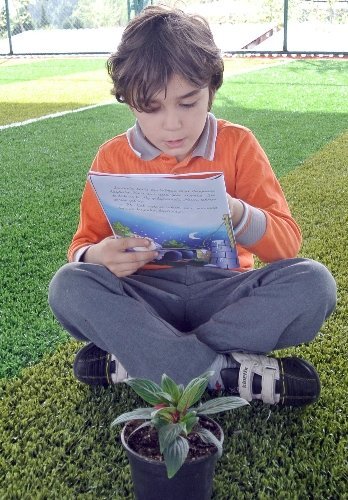 Öğrenciler çiçeklere kitap okuyor