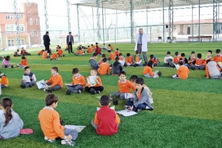 Öğrenciler çiçeklere kitap okuyor