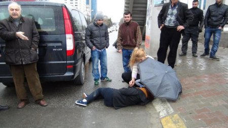 Şemsiye ve atkısıyla yaralı kızı yağmurdan korudu