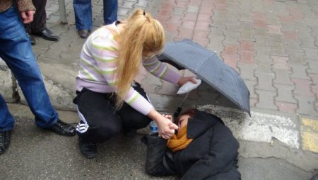 Şemsiye ve atkısıyla yaralı kızı yağmurdan korudu